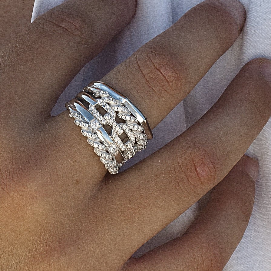 Anillo ancho de plata de ley 925 con diseño entrelazado y circonitas blancas.