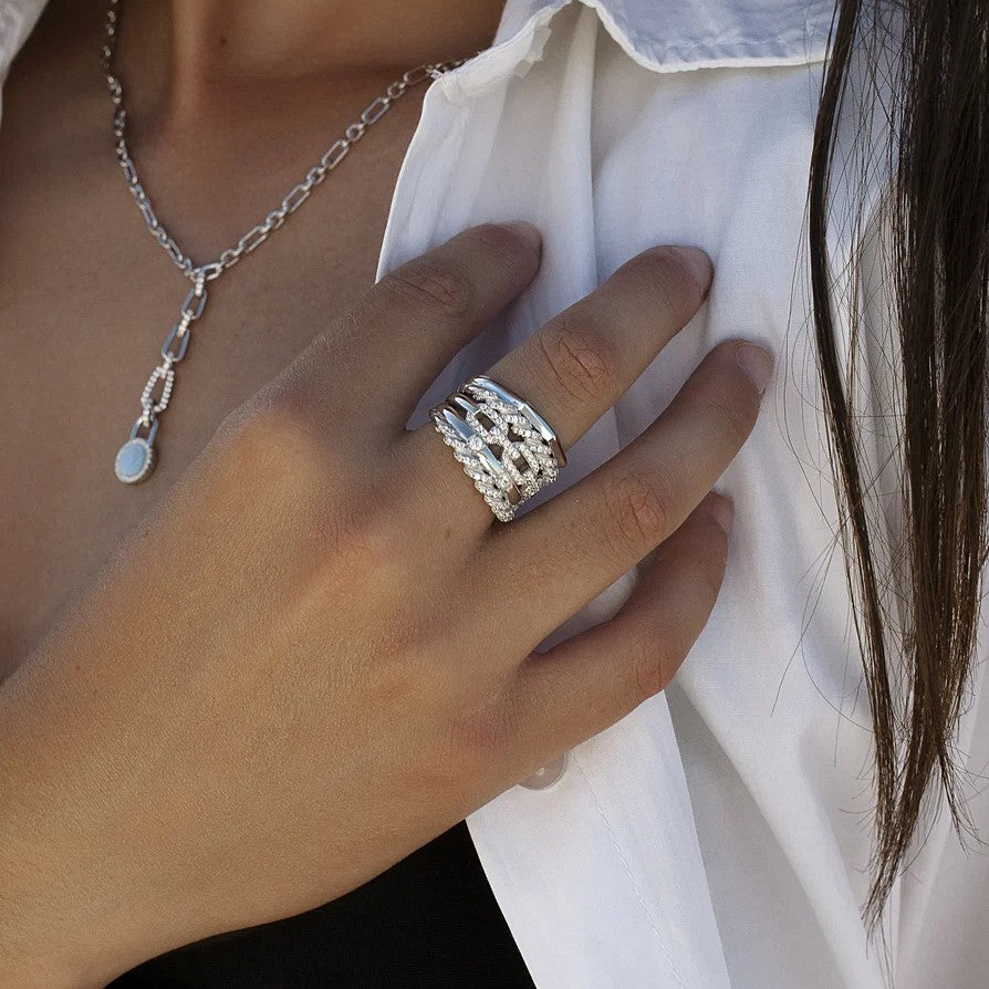 Anillo ancho de plata de ley 925 con diseño entrelazado y circonitas blancas.