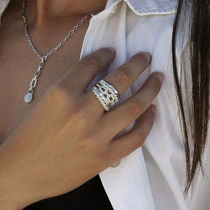 Anillo ancho de plata de ley 925 con diseño entrelazado y circonitas blancas.