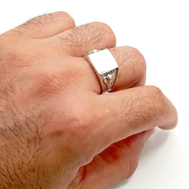 Anillo sello cuadrado de plata de ley con grabado de cobra puesto en el dedo