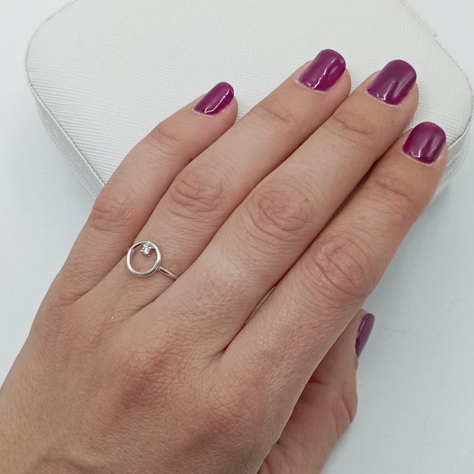 Anillo con circonita circular en plata de ley 925 bañada en rodio, puesto en el dedo