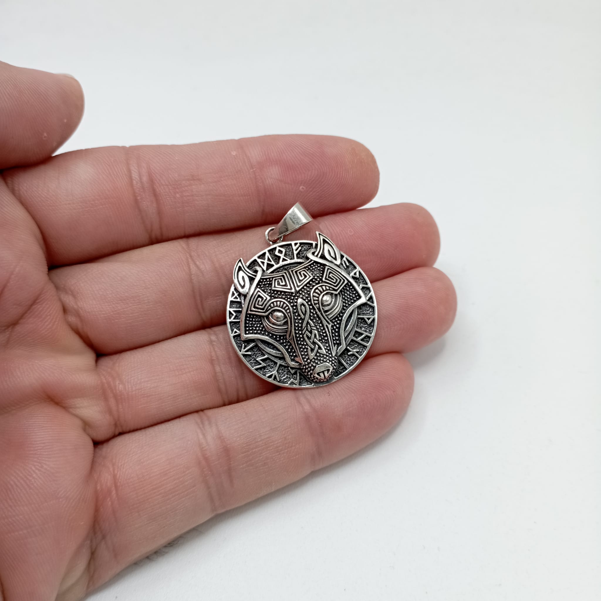 Colgante grande de plata de ley 925 lobo vikingo redondo con runas sujetado en la mano