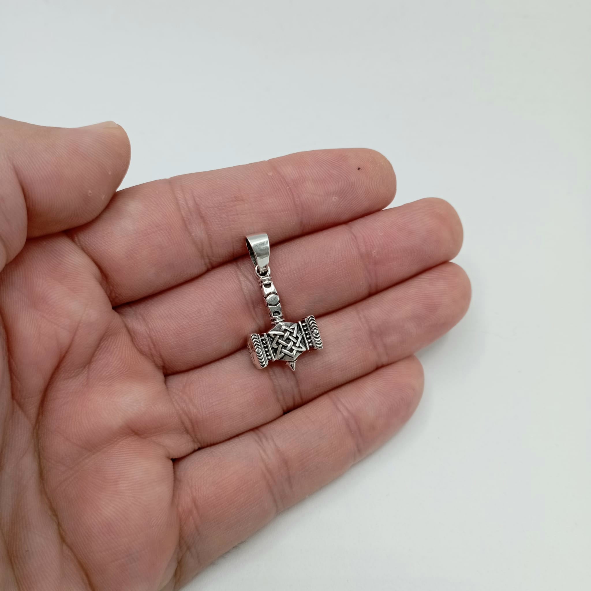 Colgante de plata de ley 925 en forma de maza, detallado con runas vikingas que representa a Mjolnir, el martillo de Thor sujetado en una mano