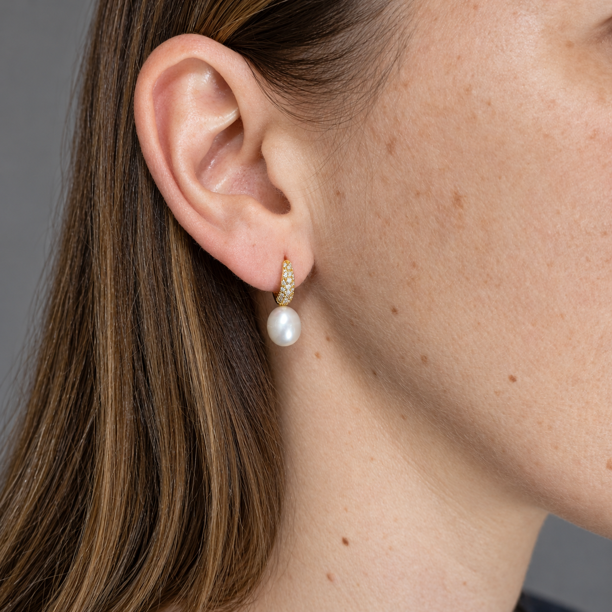 Pendientes de plata chapada en oro arito con circonitas y una perla, puestos en la oreja