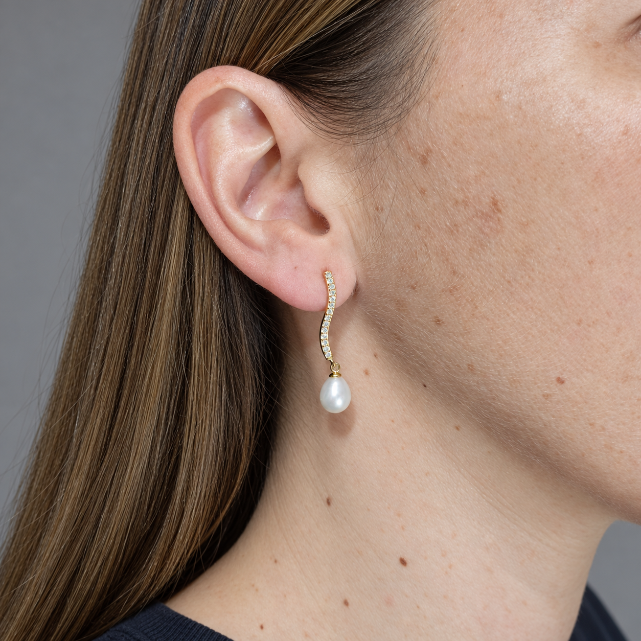 Pendientes de plata chapada en oro tira ondulada con circonitas y perla cultivada, puestos en la oreja