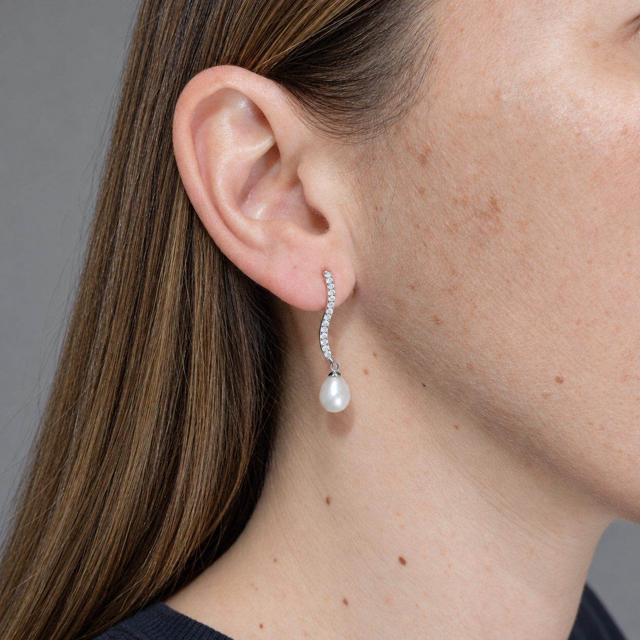 Pendientes de plata tira ondulada con circonitas y perla cultivada, puestos en la oreja