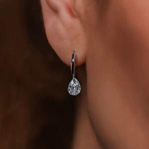 Pendiente de aro huggie de plata de ley 925 rodiada con circonita en talla gota, puesto en la oreja