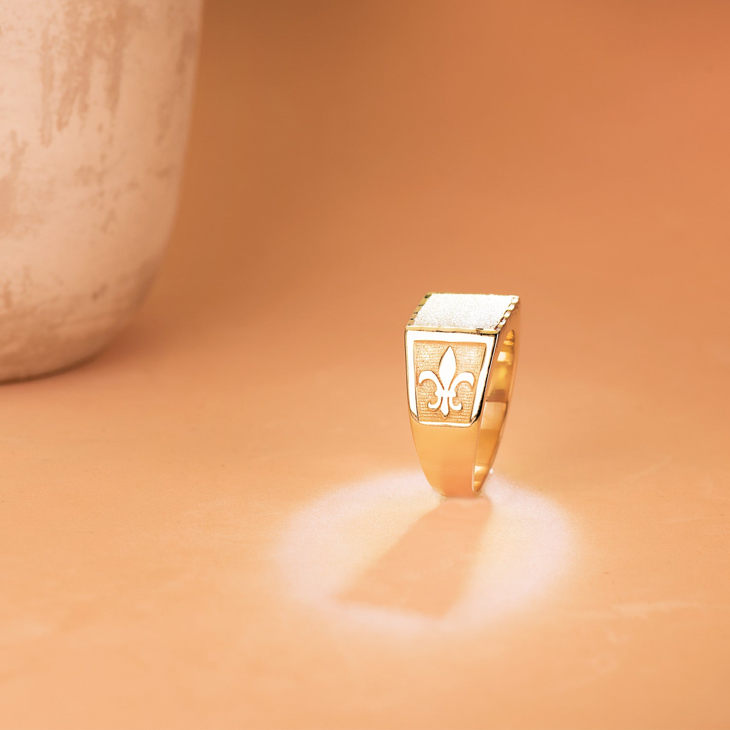 Detalle de sello cadete de oro de ley 18k macizo con flor de lis tallada, frente de 11,5x11 mm