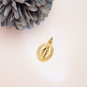 Medalla de la Virgen Milagrosa, en oro de ley 18k de 28x18 mm, colgando de una cadena sobre fondo claro