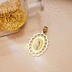 Medalla de la Virgen Milagrosa en oro de ley 18k de 33x22 mm sobre una superficie clara junto a un frasco de cristal