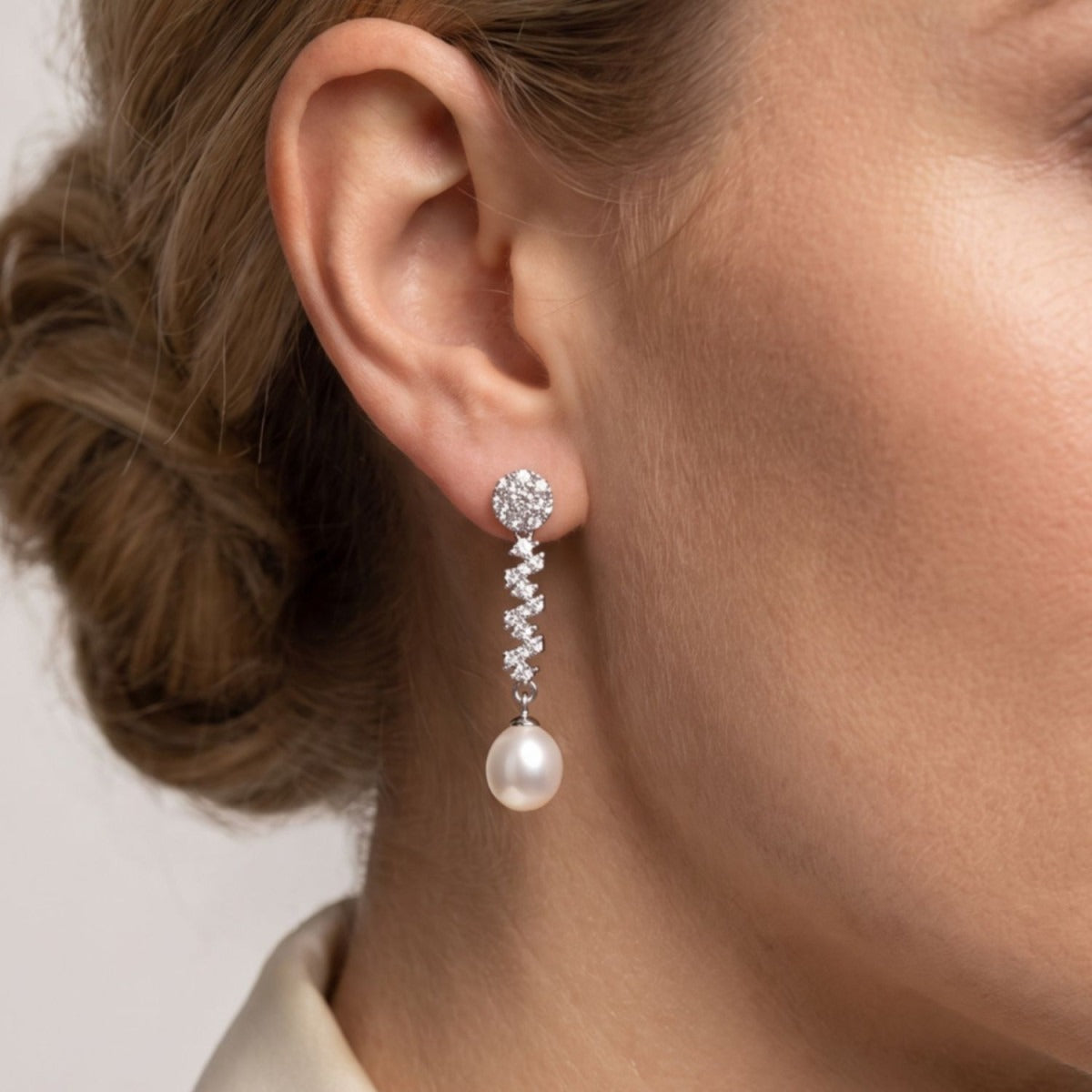 Pendientes zigzag plata de ley con circonitas blancas puestos en la oreja