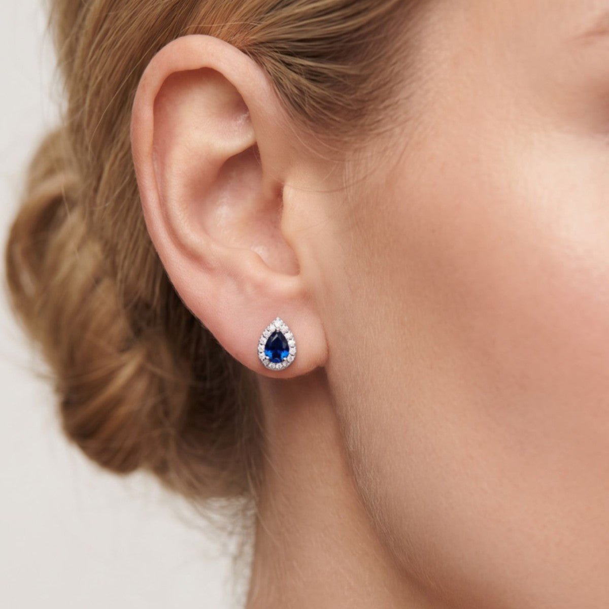 Pendientes gota plata de ley con circonita azul zafiro puestos en la oreja