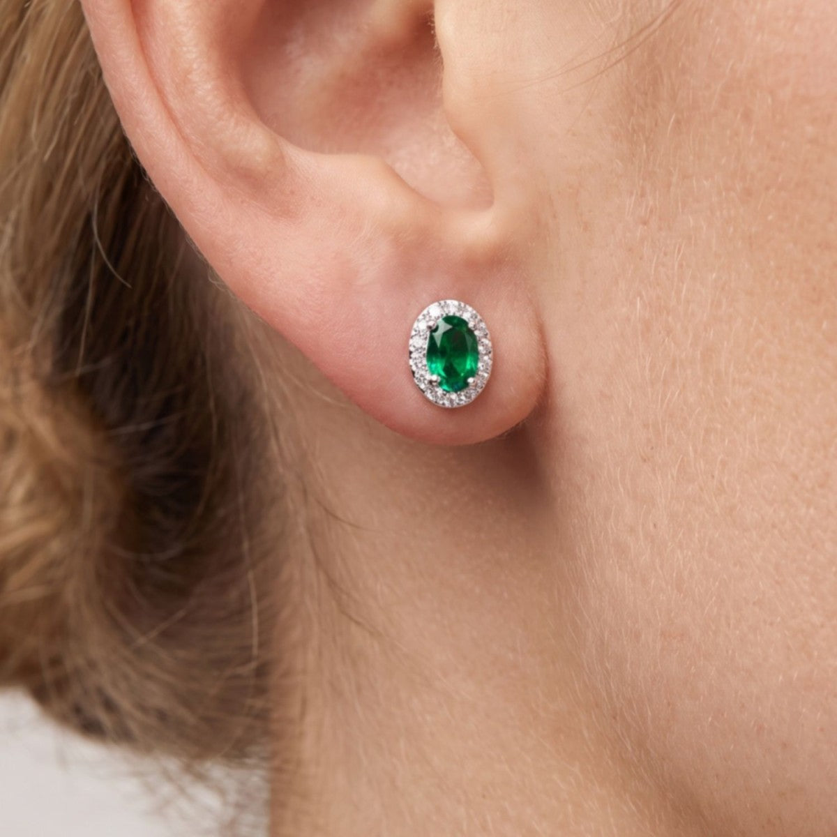 Pendientes óvalo plata de ley con circonita verde esmeralda puestos en la oreja