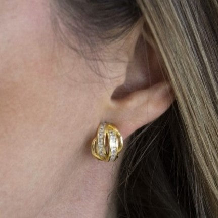 chica con Pendientes plata 925 chapada en oro, aros cruzados con circonitas en raíles. Cierre omega. Diseño elegante.